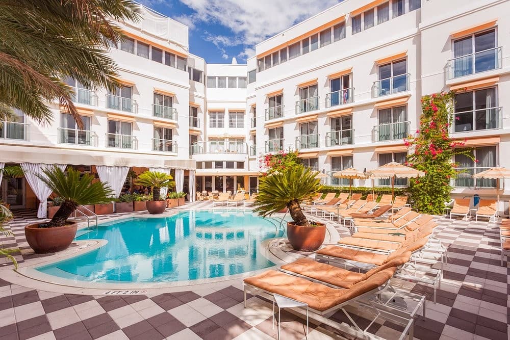 The Art Deco pool courtyard at The Plymouth, South Beach, framed by palms and the hotel's white balconied wings
